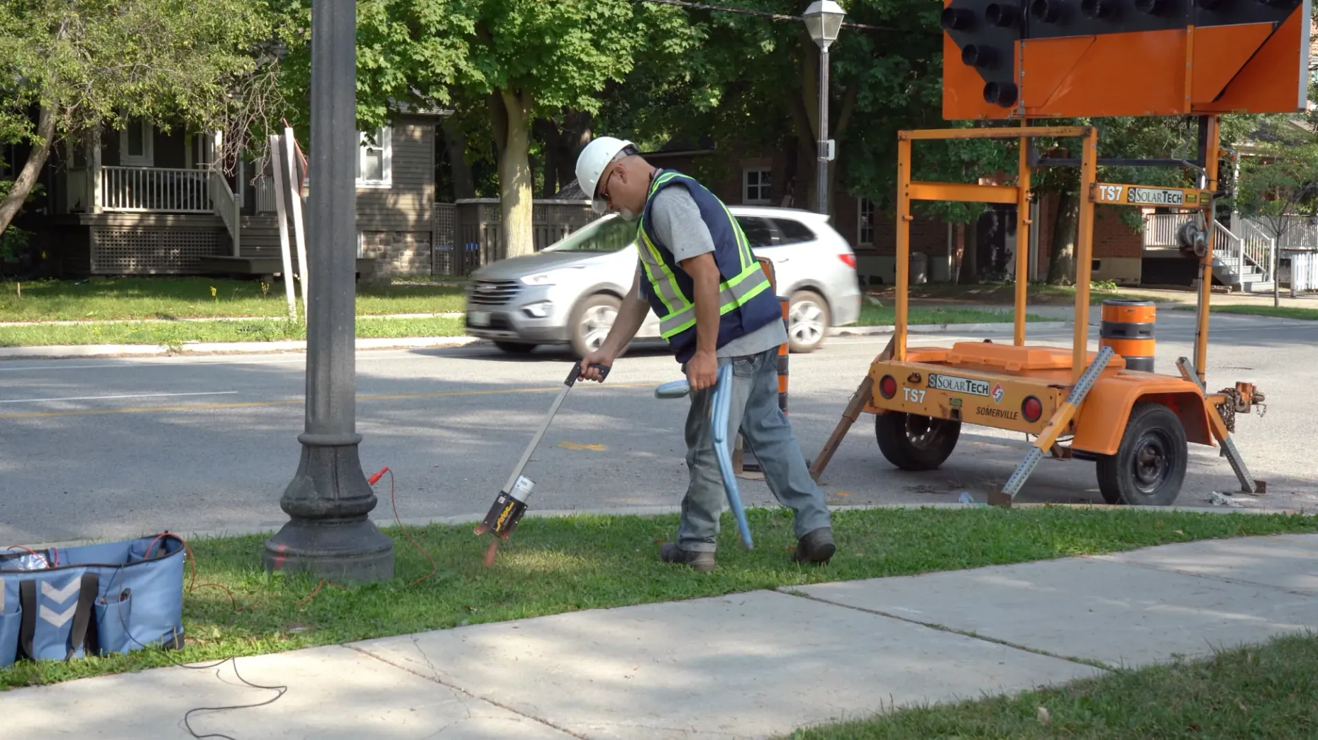 CLI technician marking a boulevard beside a traffic-control trailer on a residential street