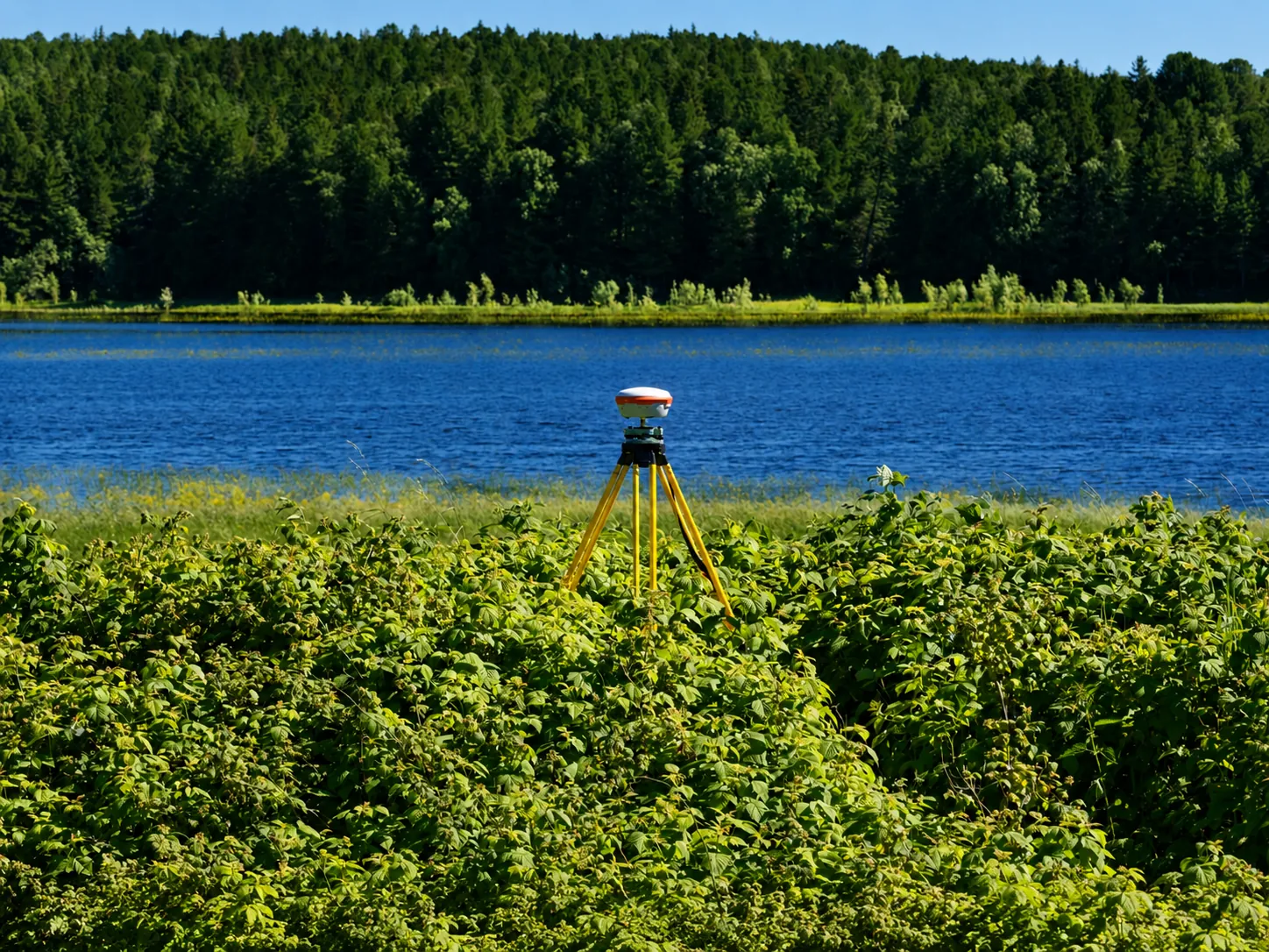GNSS survey tripod collecting location data beside a lake