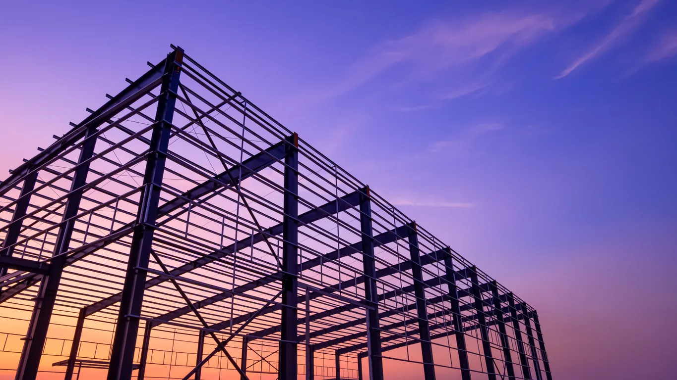 Steel building frame under construction at sunset