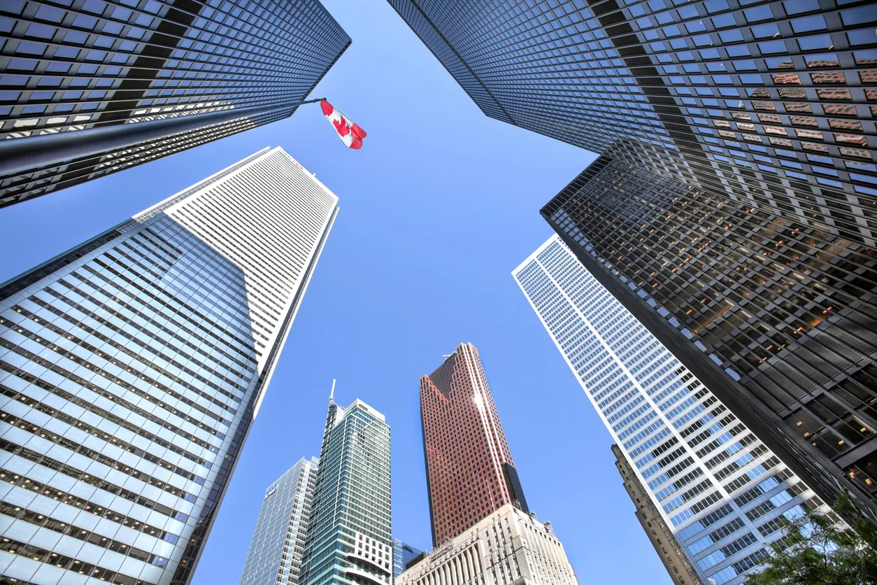 Downtown Toronto office towers with a Canadian flag, viewed from street level