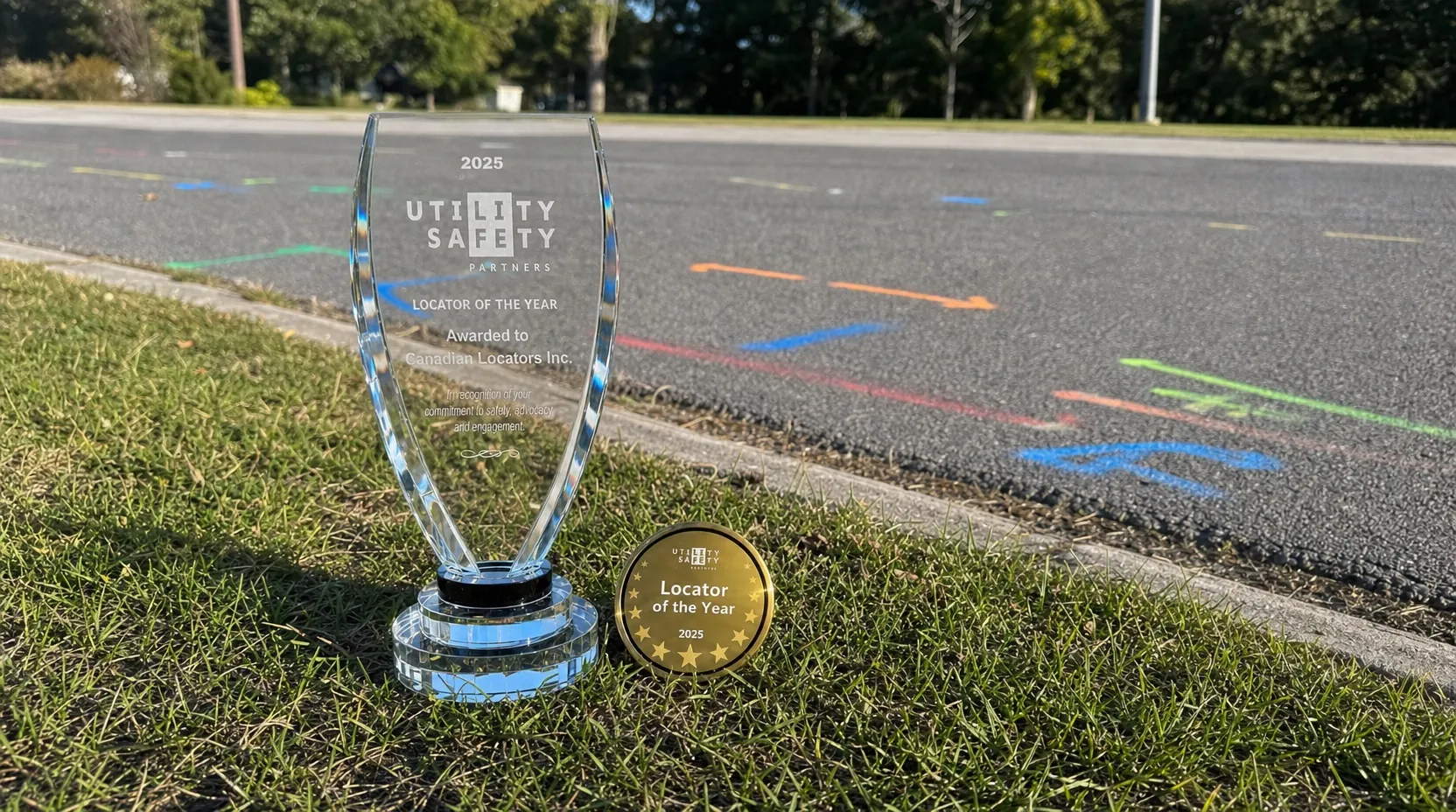 2025 Utility Safety Partners Locator of the Year trophy and gold badge on the grass beside marked pavement